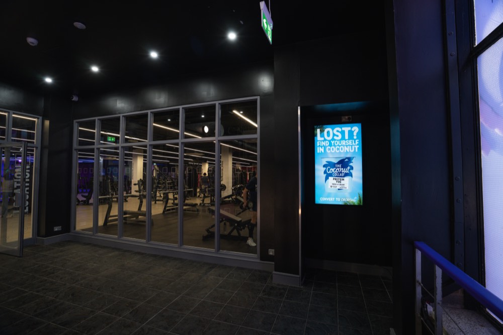 Vertical digital signage screen displaying advertising content in a fitness club