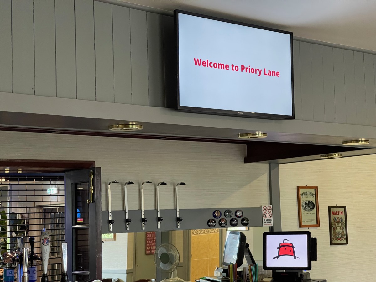 Digital signage screen welcoming guests above a football clubhouse bar