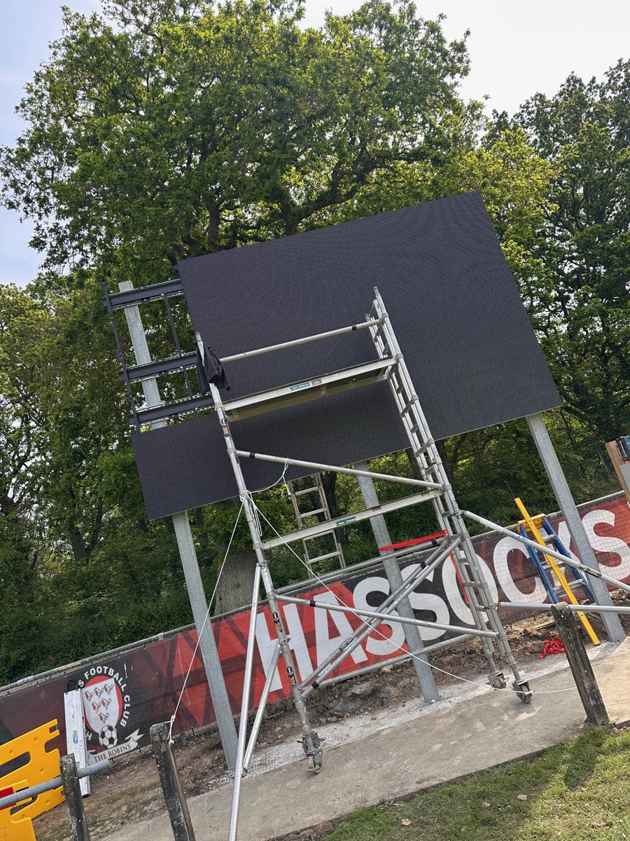 Large outdoor LED video wall under construction on a scaffold tower