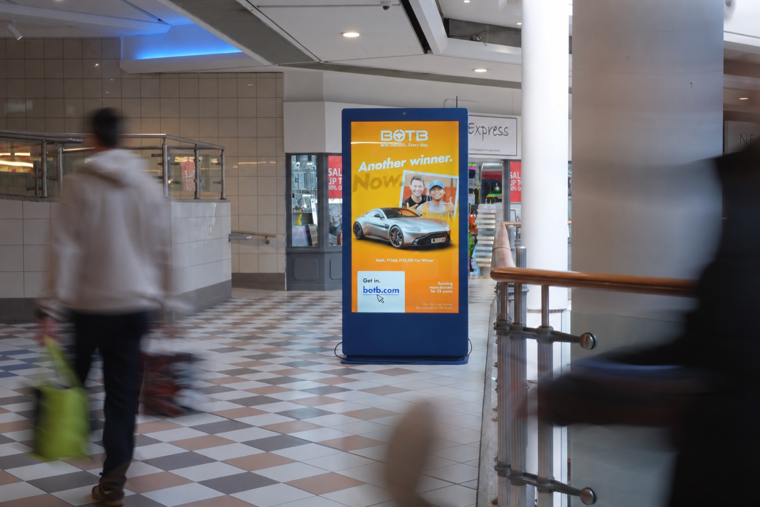 Digital advertising screen in a shopping centre with passing shoppers